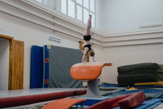 Ginasta realiza uma parada de mãos sobre o aparelho de salto em um ginásio de treinamento.