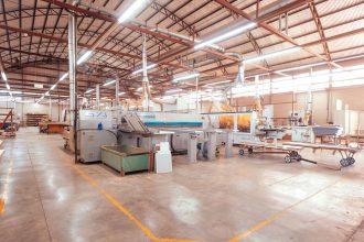Vista ampla do interior de uma fábrica organizada, com máquinas industriais modernas e equipamentos de produção.