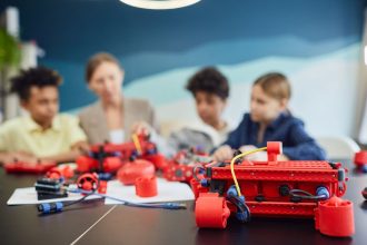 Crianças trabalham juntas na construção de um projeto de robótica em uma atividade educativa